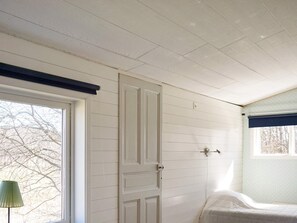 A room with a bed, a window with a view of bare trees, and a door with a light switch on the wall. - 4 Person Holiday Home in Hedekas (Hedekas)