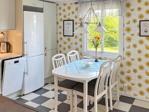 Une cuisine avec un réfrigérateur blanc, un guide sur le café et une fenêtre donnant sur un paysage verdoyant.