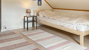 A bedroom with a sloped ceiling, a bed, a nightstand with a lamp, and two framed pictures on the wall. - 4 Person Holiday Home in Hedekas (Hedekas)