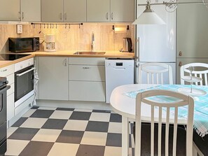 A compact kitchen with a microwave, coffee maker, and dishwasher. There is a dining table with chairs and a checkered floor. - 4 Person Holiday Home in Hedekas (Hedekas)