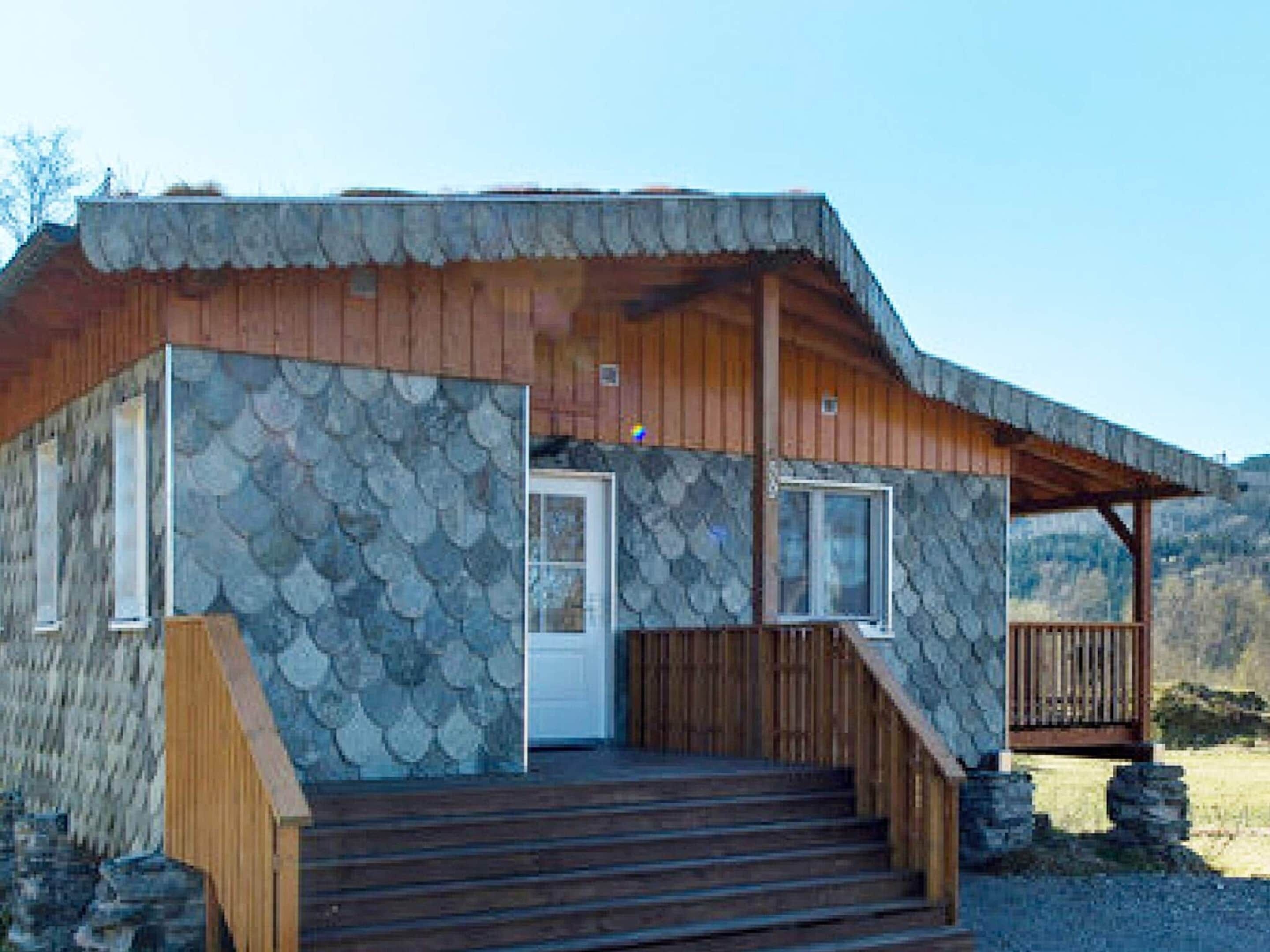 A cabin with a stone exterior, wooden steps, and a porch.