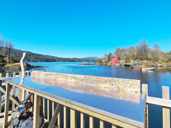 A wooden dock extending into a calm lake with boats, a red building, and forested hills in the background. - 4 Star Holiday Home in Lonevag (Osteroy)