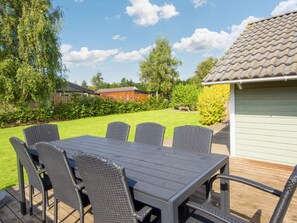 An outdoor patio with a table and chairs, surrounded by a lawn and a building with a tiled roof. - 8 Person Holiday Home in Sydals (Sydals)