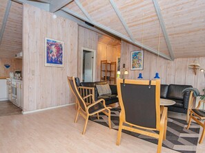 A spacious loft with a high ceiling, wooden walls, a dining area with a table and chairs, a black leather sofa, and a kitchen area. - 8 Person Holiday Home in Sydals (Sydals)