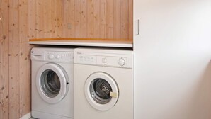 Une buanderie équipée de deux machines à laver à chargement frontal et dotée d’un plafond en bois.