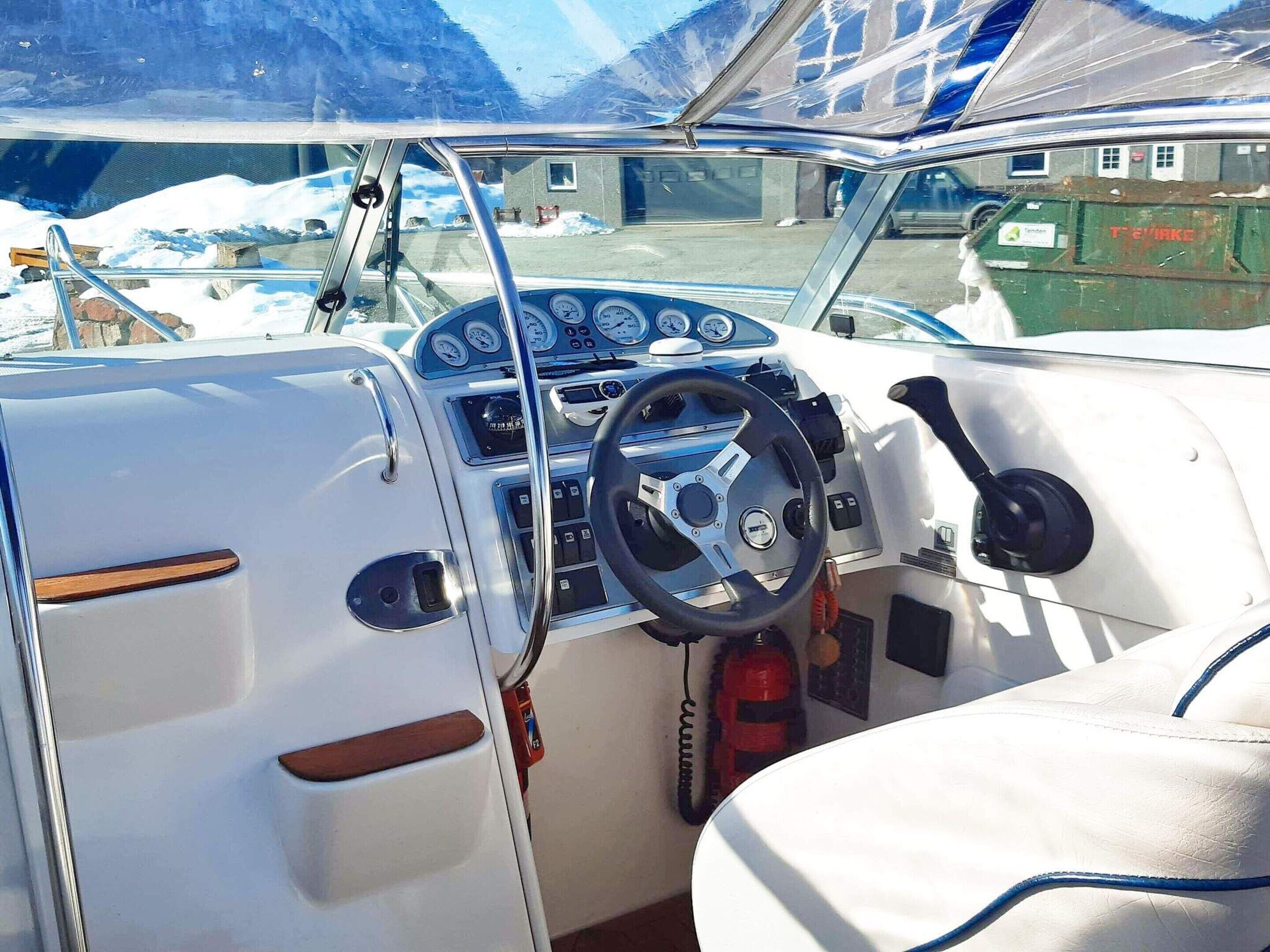 A boat's interior with a steering wheel, gauges, and a control panel.