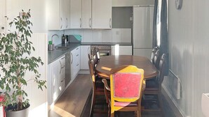 A compact kitchen with white cabinets, a dining table with chairs, and a potted plant. - 4 Star Holiday Home in Averoy (Averoy)