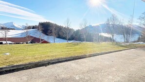 A rural landscape with a clear sky, a road, a grassy field, and a red-roofed building. - 4 Star Holiday Home in Averoy (Averoy)