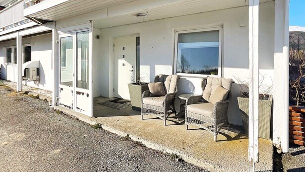 A white building with a covered porch, outdoor seating, and a view of the landscape. - 4 Star Holiday Home in Averoy (Averoy)