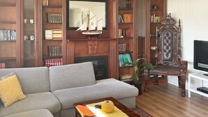 A living room with a grey sofa, a wooden coffee table, a fireplace, and a bookshelf filled with books. - 4 Star Holiday Home in Averoy (Averoy)