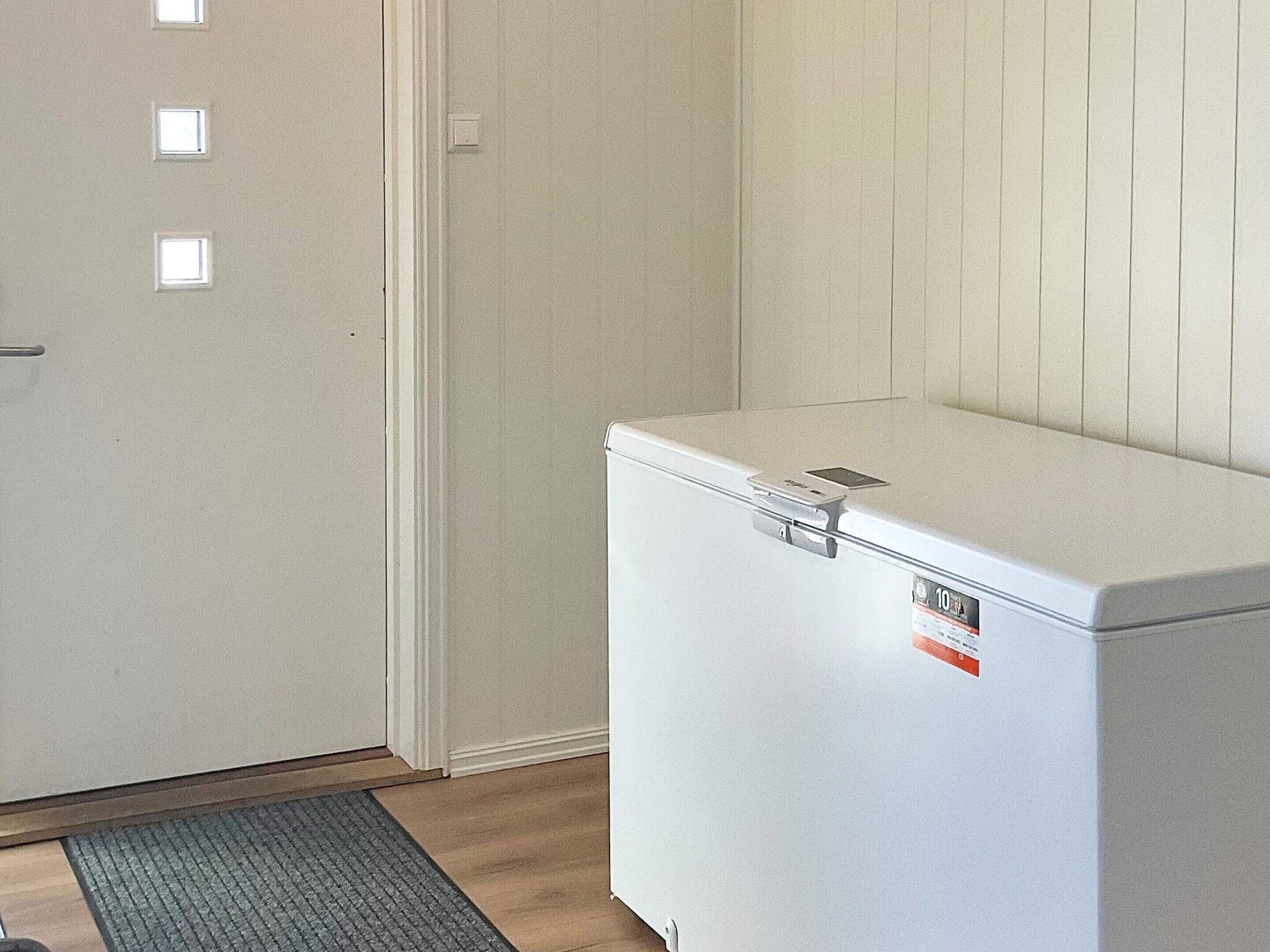 A compact, white utility room with a door, a small window, and a white appliance with a sticker.