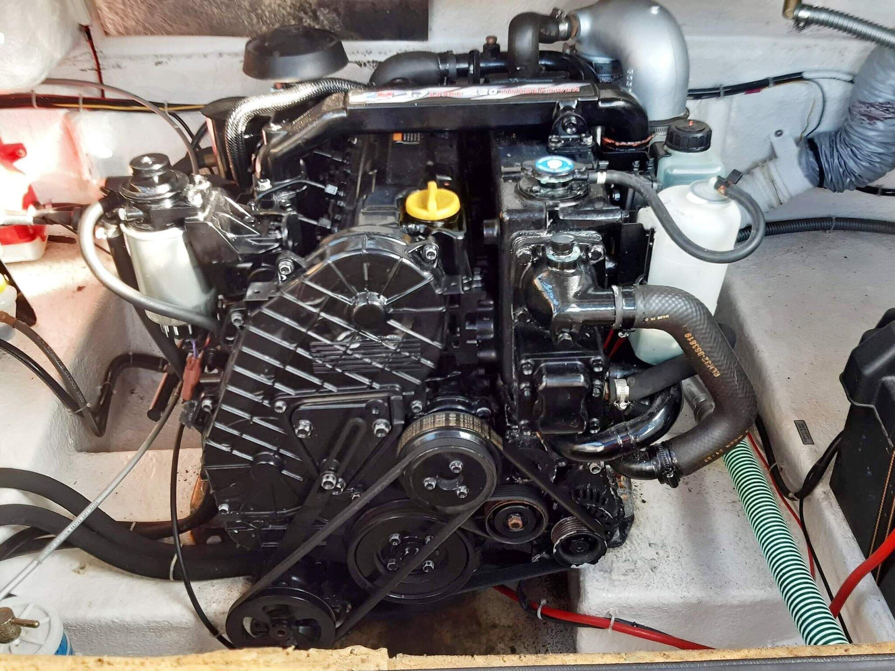 An engine compartment with visible hoses, a yellow cap, and various mechanical components.