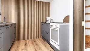 A modern kitchen with wooden slat walls, a built-in oven, and a coffee machine. - 5 Person Holiday Home in Borkop (Borkop)