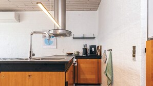 Una cocina moderna con campana extractora de acero inoxidable, armarios de madera, encimera negra y suelo de baldosas.