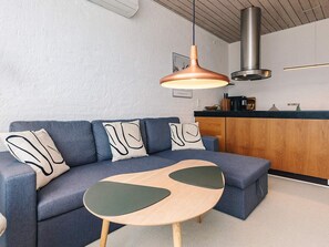 Un soggiorno moderno con un divano blu, un tavolino in legno e una lampada a sospensione.