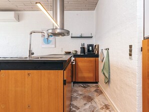A kitchen with a stainless steel range hood, wooden cabinets, a black countertop, and a tiled floor. - 4 Person Holiday Home in Vestervig (Vestervig)