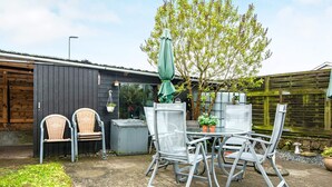 An outdoor patio with a table and chairs, surrounded by a wooden fence and a garden area. - 6 Person Holiday Home in Skaerbaek-by Traum (Skaerbaek)