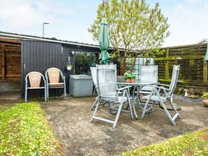 An outdoor patio with a table and chairs, surrounded by a wooden fence and a garden area. - 6 Person Holiday Home in Skaerbaek-by Traum (Skaerbaek)