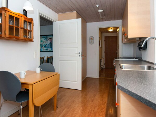 A compact kitchen with a wooden table and chairs, a built-in cabinet, and a countertop with a sink.
