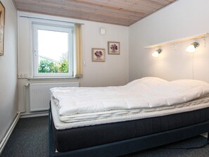 A bedroom with a bed, a window, a radiator, and wall-mounted lights.