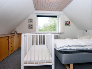 A bedroom with a crib, a bed, a dresser, a window, and a radiator. - 6 Person Holiday Home in Skaerbaek-by Traum (Skaerbaek)