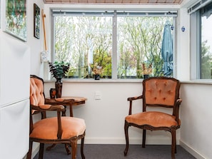 A room with two wooden chairs, a small table, and a window with a view of trees.