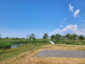 A rural landscape with a paved path, a small bridge, and a body of water.