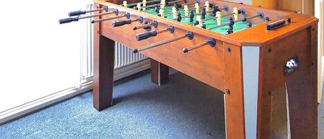 A foosball table in a room with a blue carpet and a radiator.