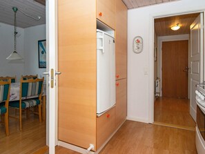 A compact kitchen with wooden cabinets, a white refrigerator, and a dining area with striped chairs.