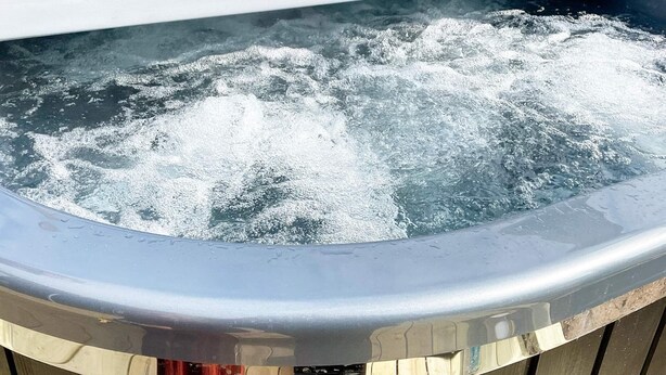 Un jacuzzi con burbujas de agua, rodeado por una terraza de madera.