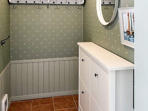 A bathroom with a white vanity, a mirror, and a patterned wall. - 6 Person Holiday Home in Munso (Munsö)
