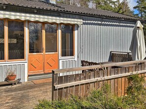 A wooden deck with a wooden fence, a potted plant, and a building with a grey exterior and a wooden door. - 6 Person Holiday Home in Munso (Munsö)
