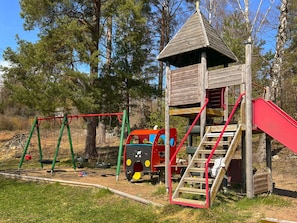 A playground with swings, a slide, and a climbing structure. - 6 Person Holiday Home in Munso (Munsö)