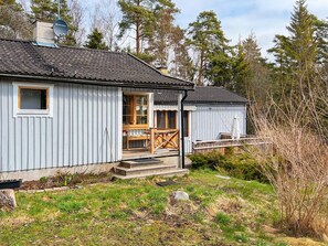 A single-story cabin with a porch, a chimney, and a satellite dish. - 6 Person Holiday Home in Munso (Munsö)