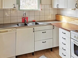 A kitchen with white cabinets, a stainless steel sink, and a wooden countertop. - 6 Person Holiday Home in Munso (Munsö)