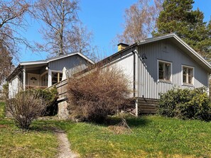 A two-story house with a porch and a stone wall. - 6 Person Holiday Home in Munso (Munsö)