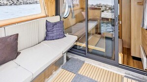 Un coin salon confortable avec un banc rembourré et une porte vitrée donnant sur une terrasse extérieure.