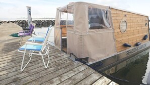 Un petit bateau de plaisance, baptisé «Emilie », était amarré à un quai en bois, doté d’un espace de repos abrité et d’une petite terrasse.