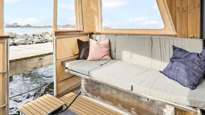 L'intérieur d'un camping-car est aménagé avec un banc rembourré, une petite table et offre une vue sur une côte rocheuse.