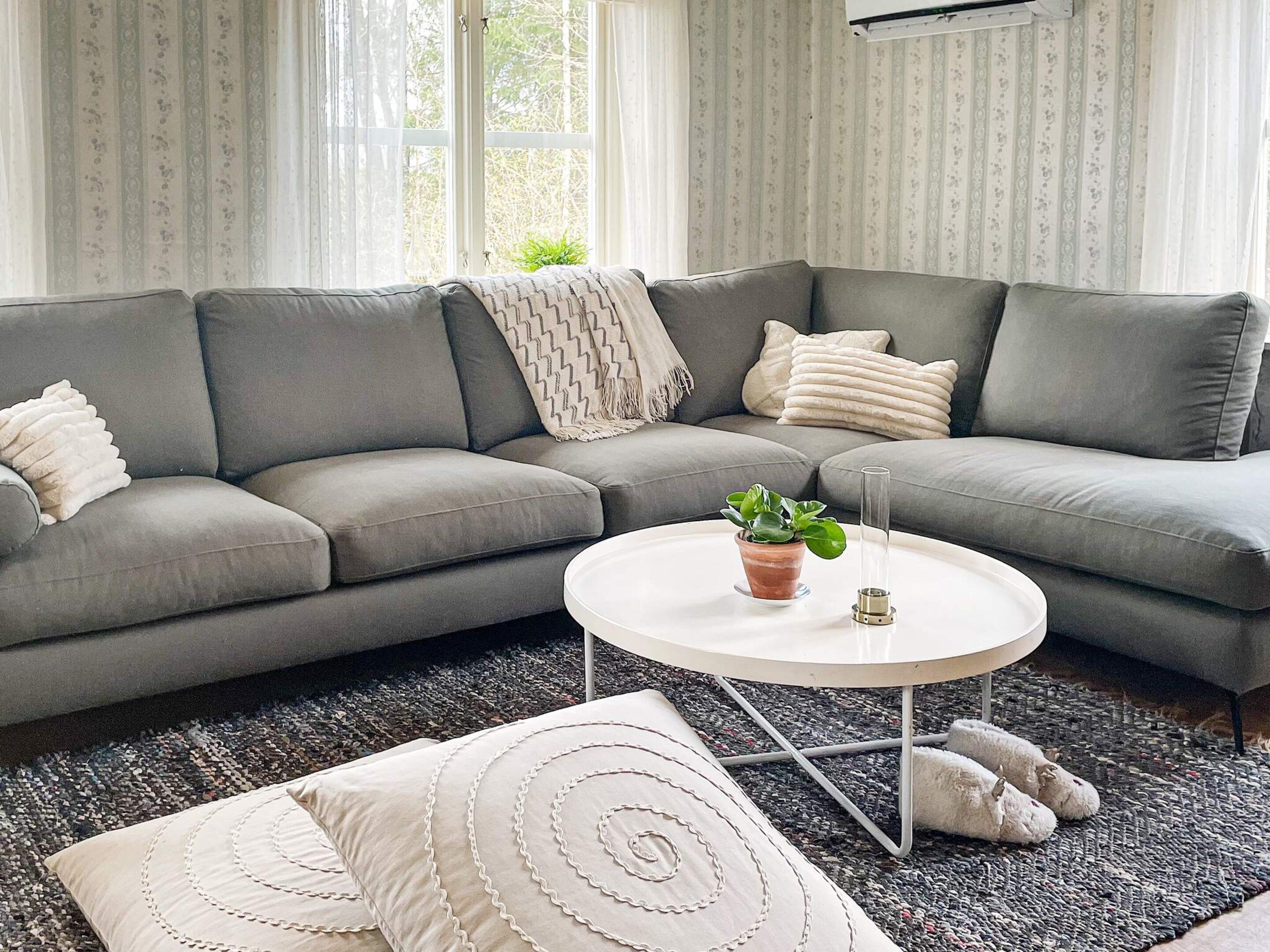 A modern living room with a grey sectional sofa, a round coffee table with a potted plant, and decorative pillows.