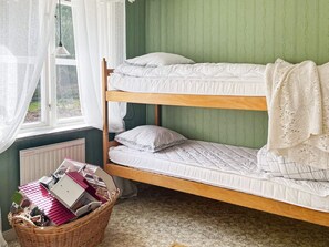 A bunk bed with white bedding, a wicker basket with books, and a window with sheer curtains. - 8 Person Holiday Home in Hestra (Hestra)