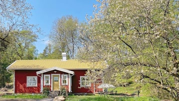 A red house with a yellow roof, surrounded by greenery and trees.