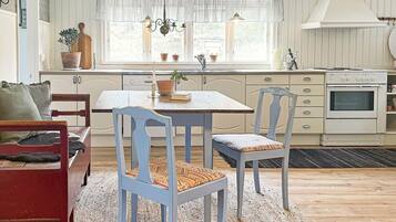 A kitchen with a dining table, chairs, a stove, and a window with curtains.