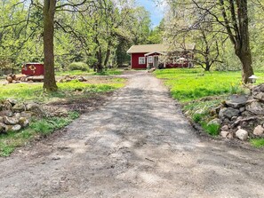 A rural pathway leading to a red house surrounded by trees and greenery. - 8 Person Holiday Home in Hestra (Hestra)