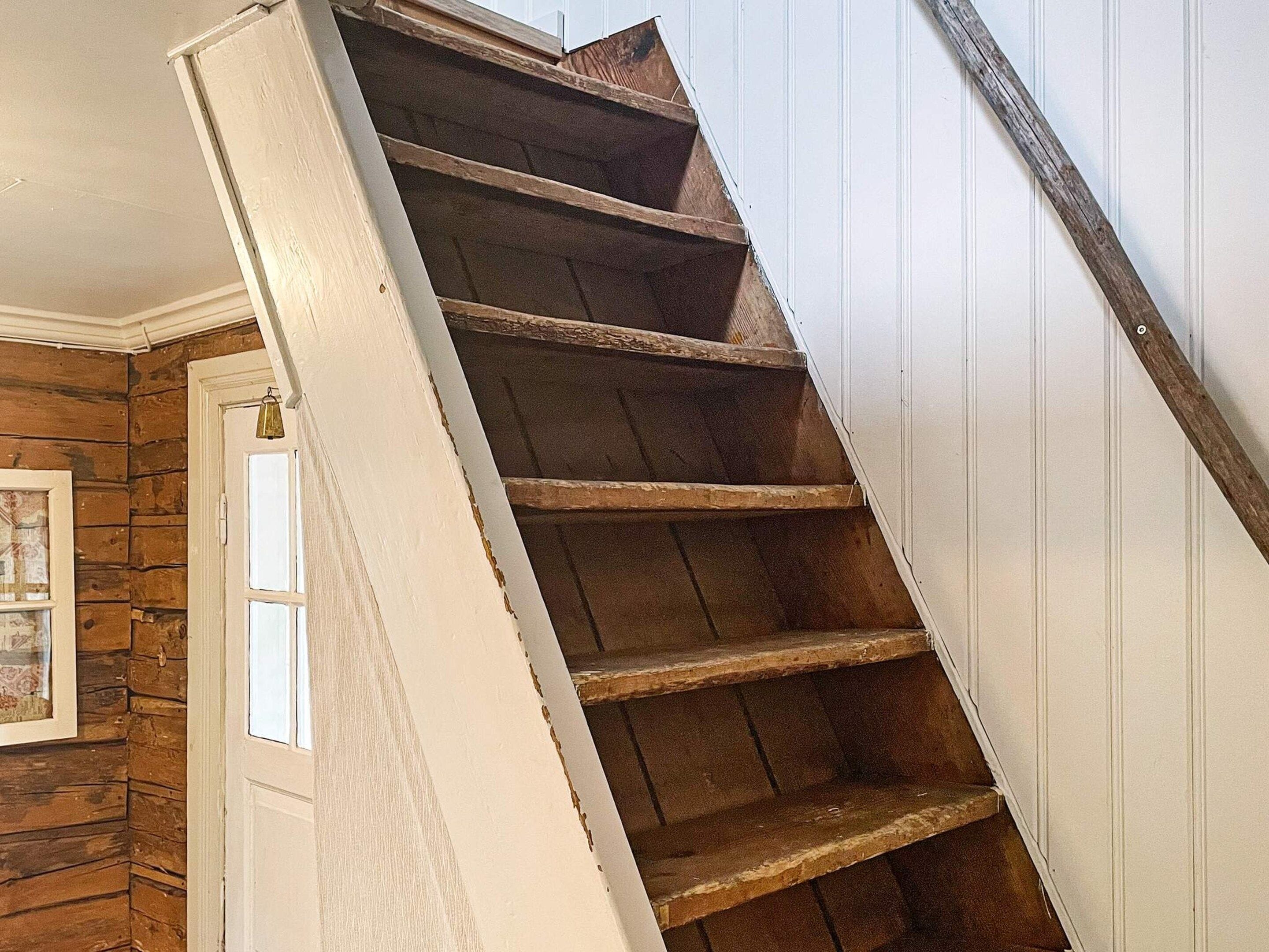 Una escalera de madera con detalles blancos sobre un muro de madera.