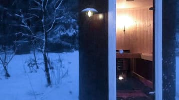 A small, wooden cabin with a single visible room containing a bed and a nightstand.