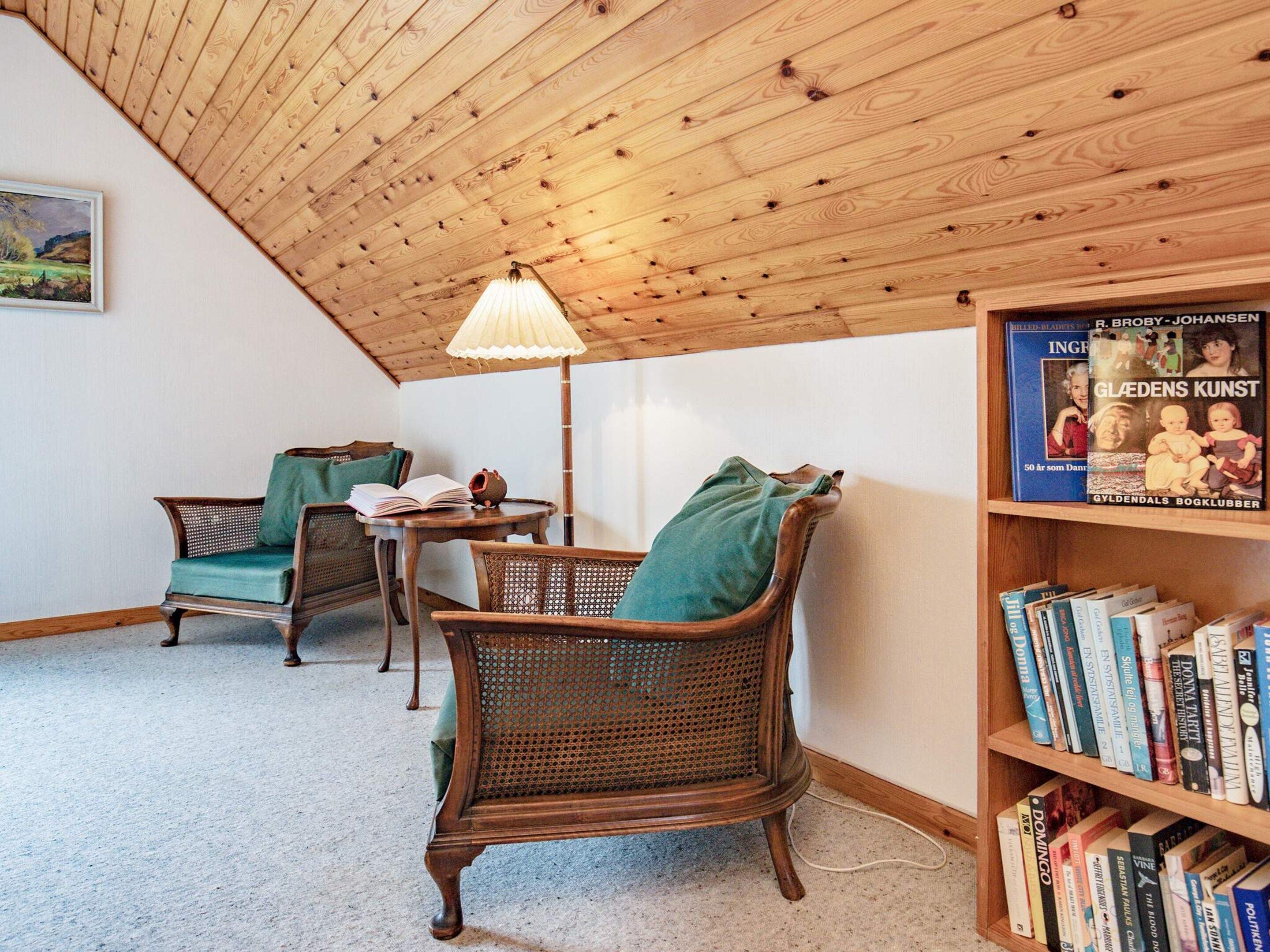 Un rincón acogedor para leer con sillones de mimbre, una mesita y una estantería llena de libros.
