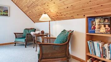 Un rincón acogedor para leer con sillones de mimbre, una mesita y una estantería llena de libros.