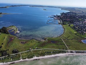 An aerial view of a coastal area with a marina, green fields, and a road. - 6 Person Holiday Home in Aeroskobing (Aeroskobing)