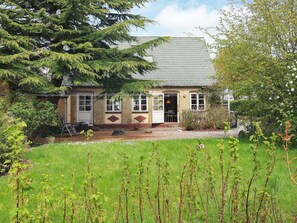 A two-story house with a front door, a small porch, and a garden with grass and plants. - 6 Person Holiday Home in Aeroskobing (Aeroskobing)